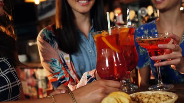Friends toasting drinks together in bar alt