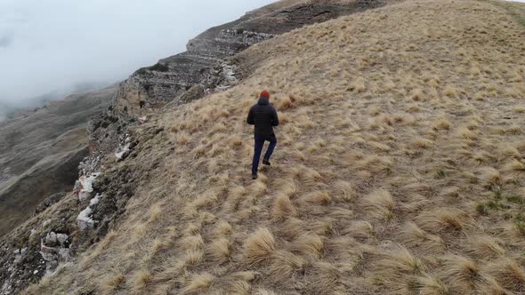Tourist Traveler Man in Tourist Clothes Walks Along the Top of a Plateau Next to a Deep Cliff Along alt