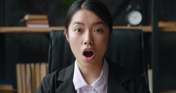 Surprised Asian Business Woman Looks at the Camera in Surprise and Says Wow While Sitting in the alt