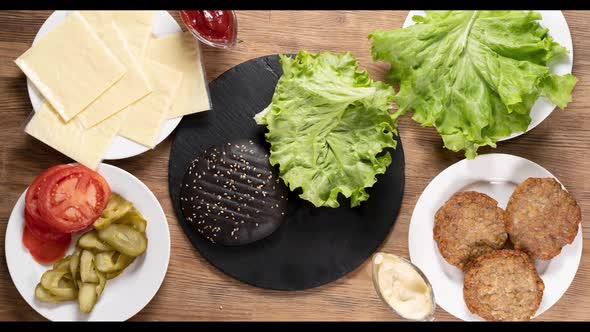 The Hamburger Ingredients That Make Up the Delicious Burger are Top View Slow Motion Black Bun alt