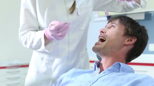 Close up of male patient showing aching tooth to dentist alt