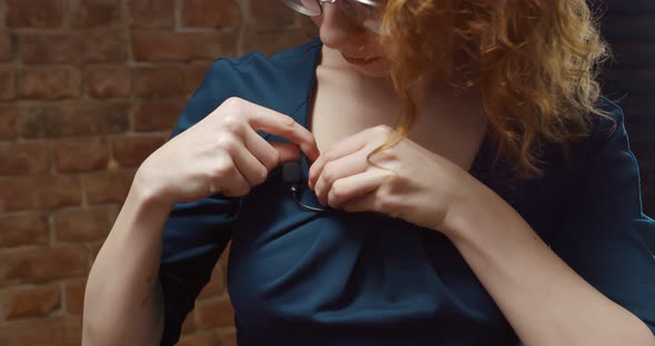 Close Up of Young Woman Attaching Lavalier Microphone To Dress Preparing for Interview alt