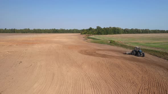 Aerial top view of a tractor, combine harvester plowing agricultural land in the spring