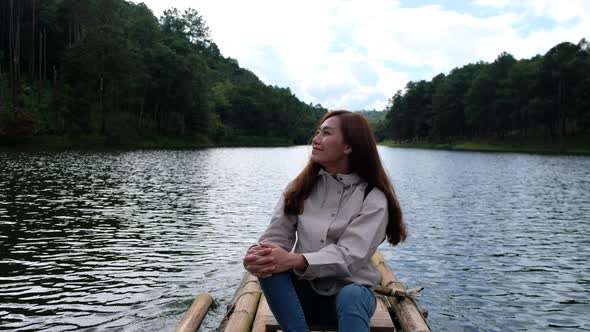 A female traveler sitting and riding bamboo raft in the lake