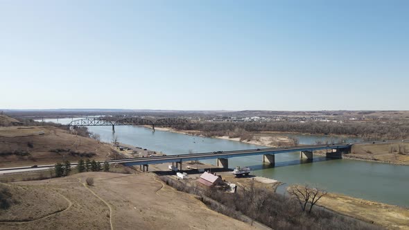 View over river with bridges in autumn blue sky. Rolling hills for hiking nearby. Ship yard on shore