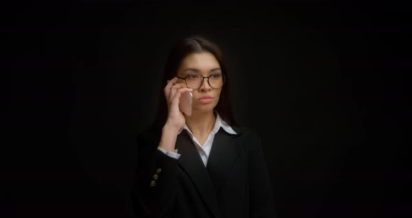 Businesswoman with Glasses and a Serious Face is Talking on the Phone