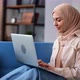 Modern Muslim Woman in Hijab Working Remotely Use Laptop Social Network Communication at Home Couch - VideoHive Item for Sale