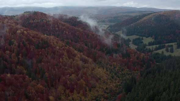 Rolling Clouds During Misty Morning Over Autumnal Forest Mountains In Romania. - Aerial Drone Shot alt