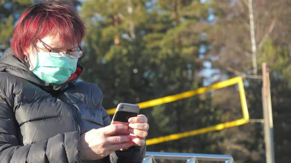 The Lady on Browsing Her Phone While on Wearing Her Face Mask in Finland