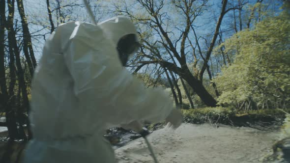 The Scientist in a Chemical Protective Suit Takes Samples of Water From the River on the Infected
