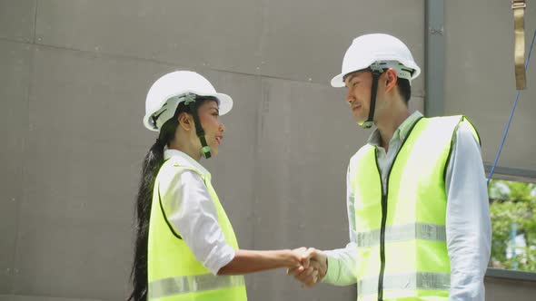 Asian structure engineer and construction worker making handshake on building working site workplace alt