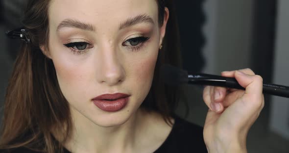 Closeup of Girl with Perfect Nude Makeup and Makeup Artist alt