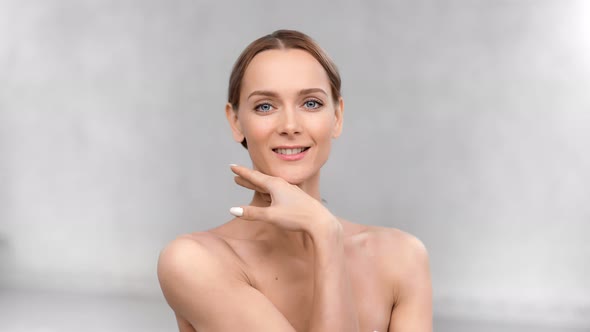 Smiling Woman with Bare Body Stroking Neck Collarbone and Face Having Positive Emotion alt