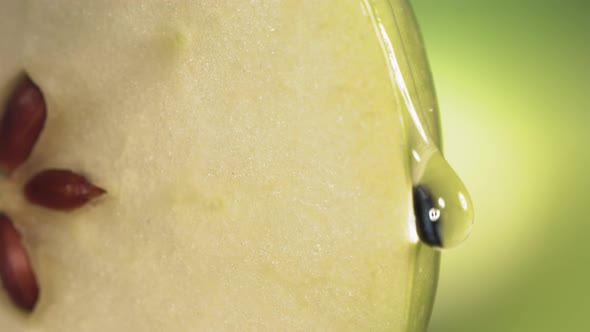 Drop of Water Flows Down the Surface of a Ripe Juicy Green Apple Slice alt