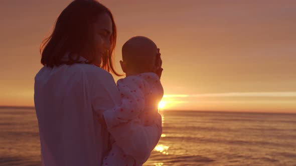Mom with baby on the background of the sea sunset