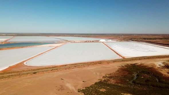Aerial footage of expansive solar evaporation salt mining fields, slide pan wide shot alt