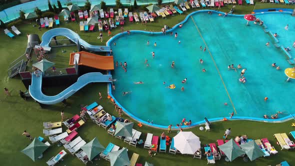People swim and have fun in the large pool at the water park. alt