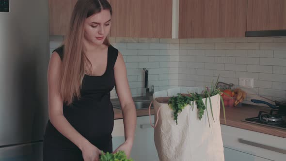 The Pregnant Woman Unpacks Products with Greens and Vegetables alt