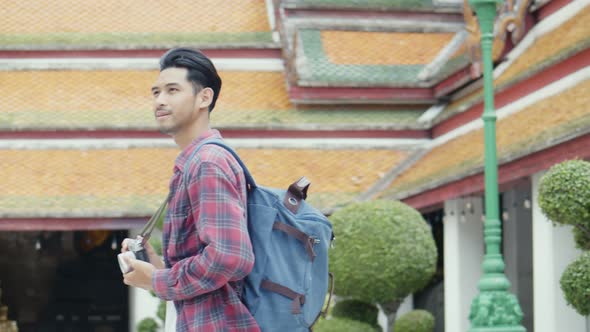 Attractive young Asian man tourists walking and looking around inside the temple and taking a photo.