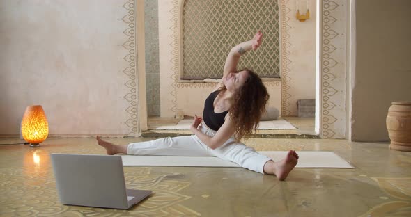 Young CurlyHaired Woman Yoga Instructor Coaching Online Making Video of Yoga Lessons on Laptop