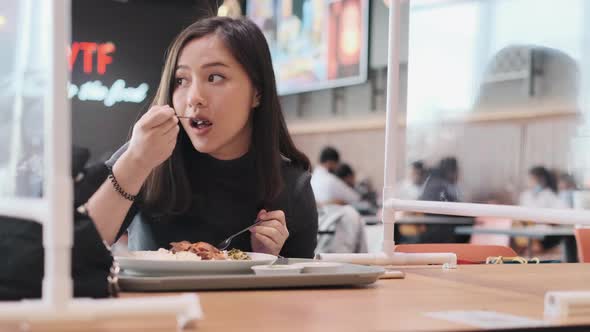 Asian woman sitting separated in restaurant eating food . alt