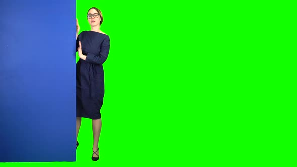 Business Woman Looks Out From Behind a Blue Board and Shows a Okey. Green Screen alt
