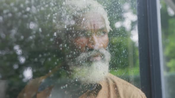 Video of sad african american senior man looking out the window alt