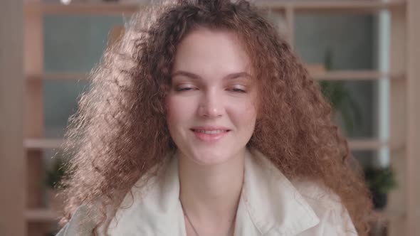Portrait of a Young Woman with Curly Hair Looks Straight Into Camera
