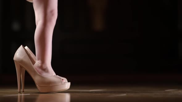 A child on a dark background is walking in his mom s shoes alt