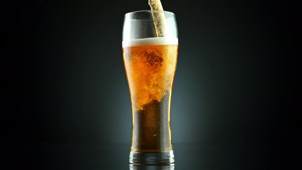 Super Slow Motion Shot of Pouring Fresh Beer Into Glass on Black Background at 1000Fps. alt