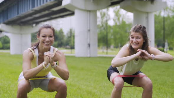 Women Do Squats with Exercise Bands in Park