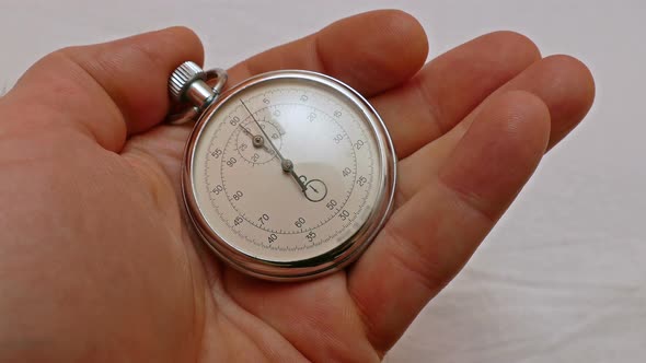 Close-up of a stop watch being started and stopped in a hand.