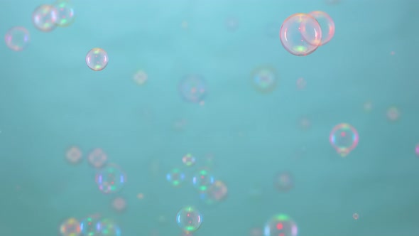Beautiful Colorful Soap Bubbles Illuminated By Pink Light Fly Indoors on a Blue Background alt