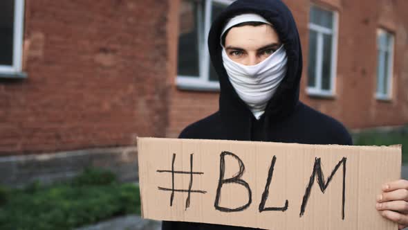 Man in Mask Stands with Cardboard Poster in Hands  BLM