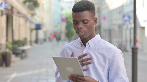 African Man Talking on Video Call on Tablet in Street alt