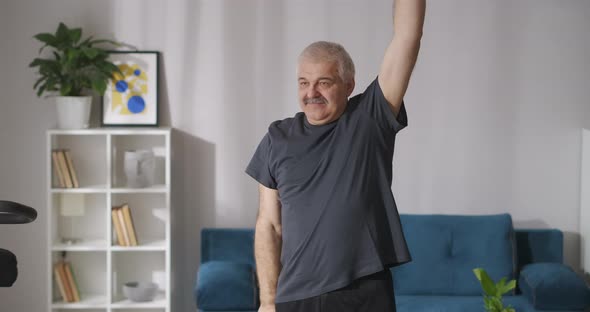 Funny Man with Moustache Is Doing Physical Exercise at Morning at Home Lifting and Lowering Hands alt