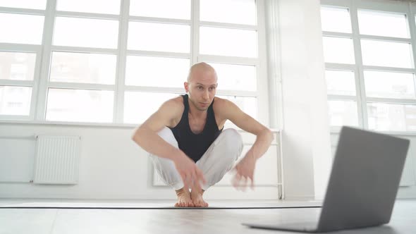 Young Bald Man Performing Complex Yoga Pose Through Online Instructions