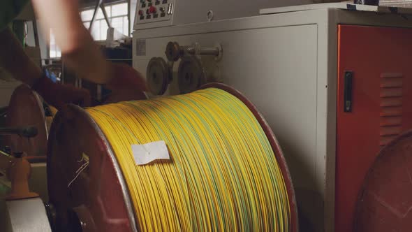 Unrecognizable Worker Rolls a Reel with Cable in Cable Production Plant Close Up