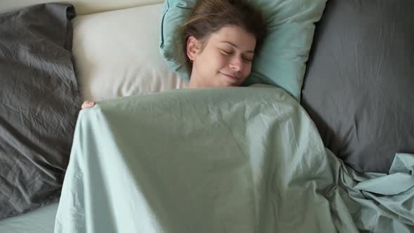 A young woman is basking in bed in the morning on a day off. alt
