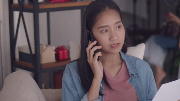 Attractive beautiful young Asian woman talking on Phone and reading documents.