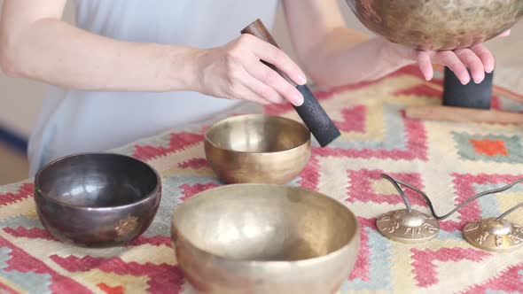 Woman Playing on Tibetan Singing Bowl While Sitting on Yoga Mat alt