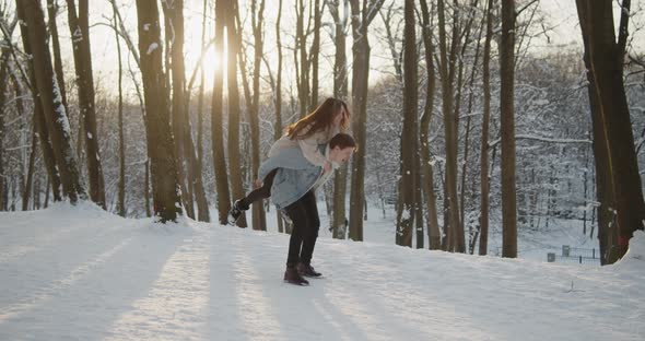 Happy Young Beautiful Couple Have Fun in Sunny Winter Forest Together alt