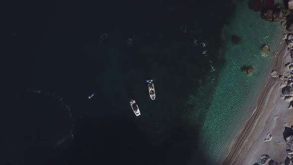 Top view of two standing motor boats and water scooter around them on emerald beach in Black sea 4k