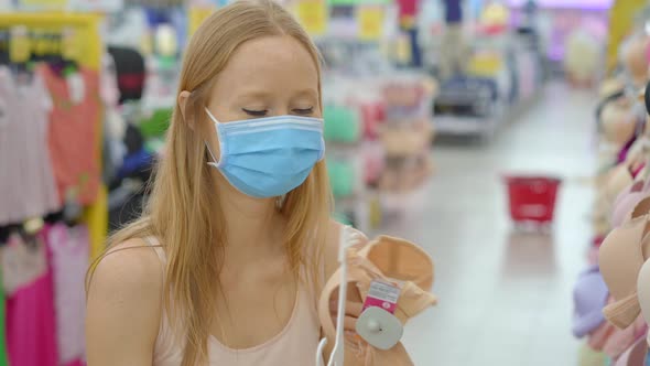 Woman in a Clothing Store in a Medical Mask Because of a Coronovirus alt