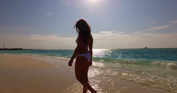 Pretty happy lady relaxing by the sea at the beach on clean white sand and blue background  alt