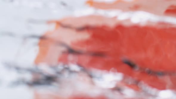 Halved pink grapefruit falling in water. Slow Motion. alt