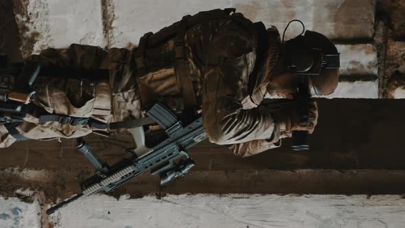 Vertical Shot of a Soldier Monitoring Eagle Eye Duty at Wrecked Building During Warfare Mission on a alt