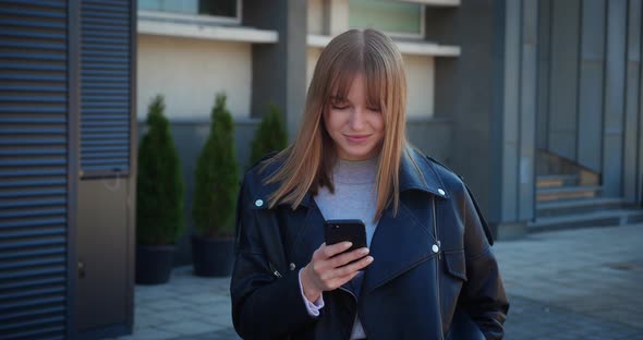 Lady Smiling Checking Smartphone Modern Urban Outfit Leather Jacket alt
