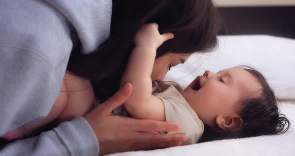 Loving Mother Tickles and Kisses Her Baby Girl