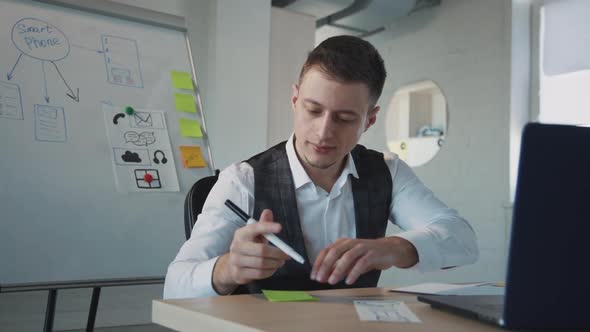 Young Man Marketer Writing Notes and Hanging Sticker on Whiteboard in Office